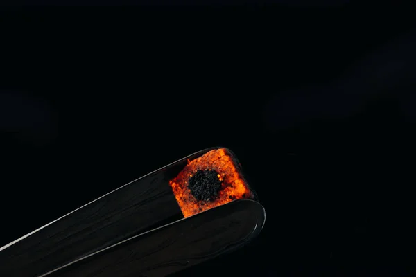 Hookah tongs and hot coal isolated on black — Stock Photo