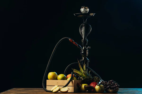 Frische leckere Früchte und Wasserpfeife auf hölzerner Oberfläche isoliert auf schwarz — Stockfoto