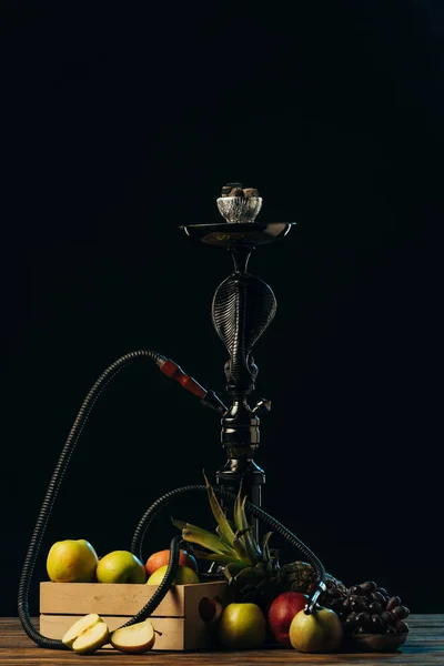 Fresh tasty fruits and hookah on wooden surface isolated on black — Stock Photo