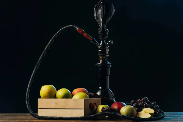 Fruits frais savoureux et narguilé sur la surface en bois isolé sur noir — Photo de stock