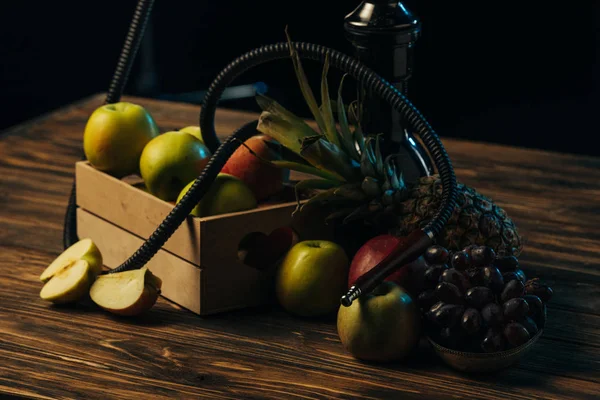 Fruits frais savoureux et narguilé sur la surface en bois isolé sur noir — Photo de stock