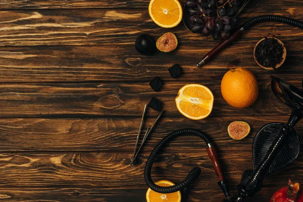 Top view of fresh fruits, coals and hookah on wooden surface — Stock Photo