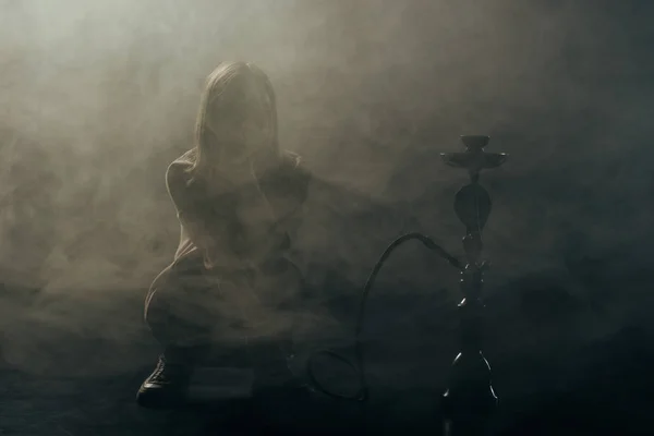 Silueta de mujer joven fumar narguile en el humo - foto de stock