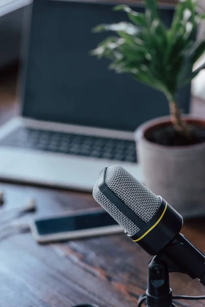 Foyer sélectif du microphone près de l'ordinateur portable et smartphone avec écran blanc sur la table en bois — Photo de stock