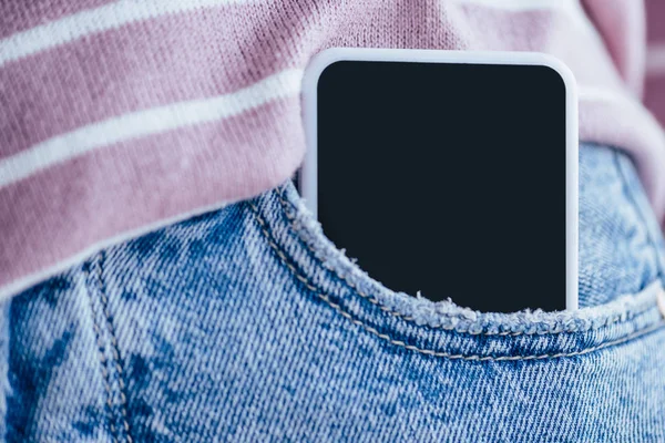 Vista recortada del hombre en jeans con teléfono inteligente en el bolsillo - foto de stock
