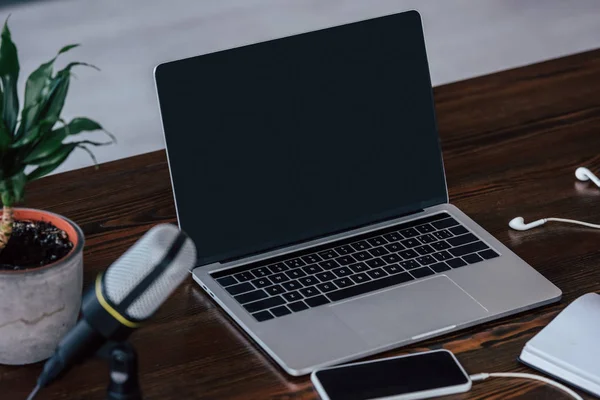 Foco seletivo de laptop e smartphone com tela em branco perto do microfone na mesa de madeira — Fotografia de Stock