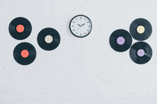 Discos de vinil e relógio redondo na parede de tijolo branco — Fotografia de Stock