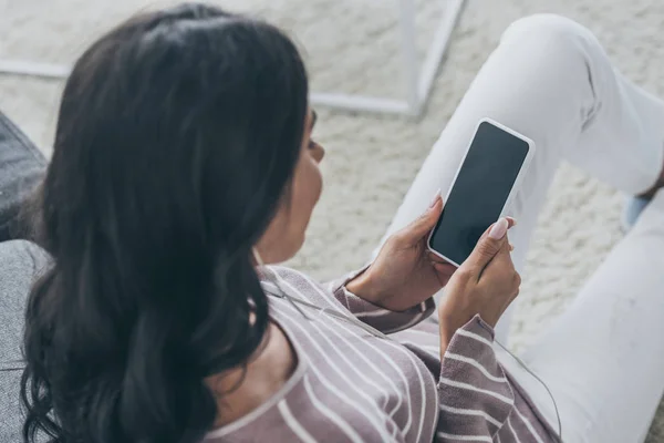 Vista aérea de la mujer sosteniendo teléfono inteligente con pantalla en blanco - foto de stock