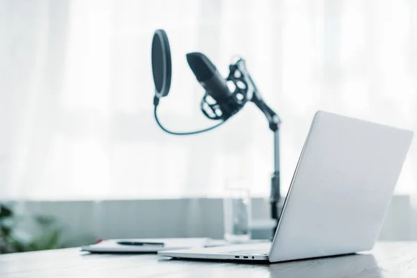 Selective focus of laptop near microphone on desk in broadcasting studio — Stock Photo