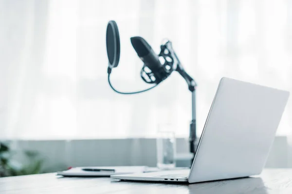 Selektive Fokussierung des Laptops in der Nähe des Mikrofons auf den Schreibtisch im Sendestudio — Stockfoto