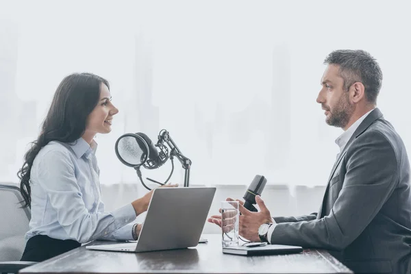 Guapo hombre de negocios hablando con bastante presentador de radio durante la entrevista en el estudio de radio - foto de stock