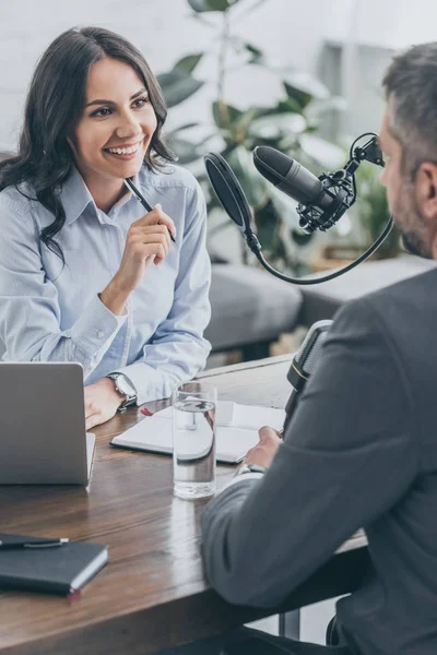 Cheerful radio host looking at businessman during interview in broadcasting studio — Stock Photo