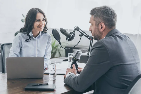 Atractivo presentador de radio sonriente entrevistando a empresario en estudio de radio - foto de stock