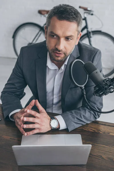 Anfitrião de rádio pensativo falando em microfone no estúdio de radiodifusão — Fotografia de Stock