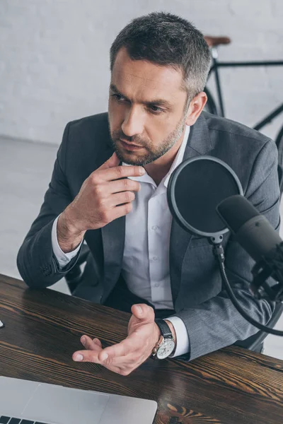 Nachdenklicher Radiomoderator gestikuliert während er im Sendestudio ins Mikrofon spricht — Stockfoto