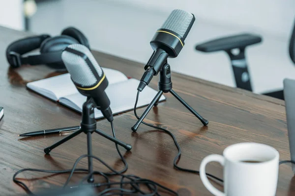 Enfoque selectivo de dos micrófonos om mesa de madera en estudio de radiodifusión - foto de stock