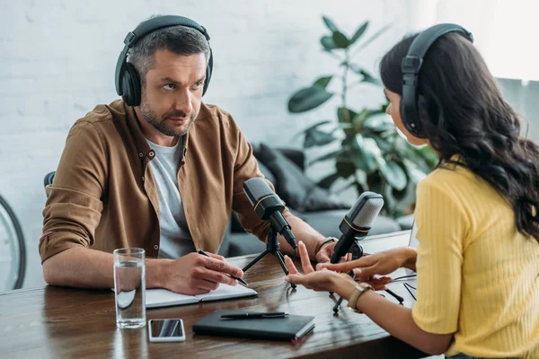 Zwei seriöse Radiomoderatoren unterhalten sich während der Aufzeichnung eines Podcasts im Sendestudio — Stockfoto