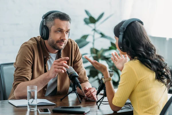 Two radio hosts talking and gesturing while recording podcast in radio studio — Stock Photo