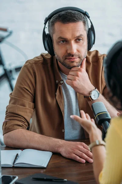 Animateur de radio attentif regardant collègue tout en enregistrant podcast en studio de radio — Photo de stock