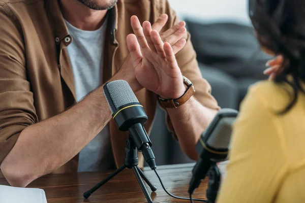 Vista cortada do host de rádio mostrando nenhum sinal durante a gravação de podcast com colega — Fotografia de Stock