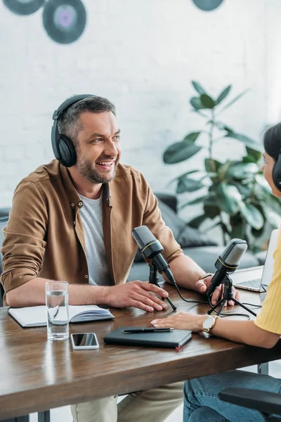 Cheerful radio hosts in headphones recording podcast in broadcasting studio — Stock Photo