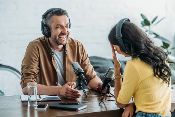 Zwei gut gelaunte Radiomoderatoren unterhalten sich während der Aufzeichnung eines Podcasts im Radiostudio — Stockfoto