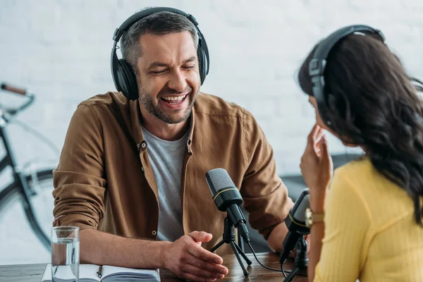 Fröhlicher Radiomoderator lacht bei Aufzeichnung von Podcast mit Kollegin — Stockfoto