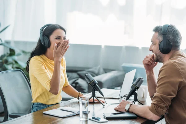 Hübscher Radiomoderator lacht während der Aufzeichnung eines Podcasts mit einem Kollegen im Radiostudio — Stockfoto