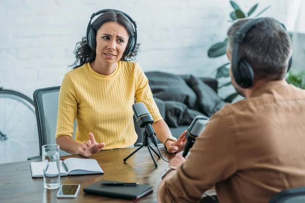 Unzufriedener Radiomoderator gestikuliert beim Blick auf Kollegin im Sendestudio — Stockfoto