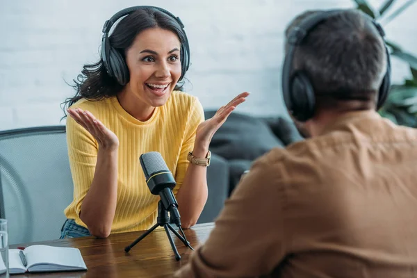 Messa a fuoco selettiva di eccitati gesti host radio mentre si guarda collega in studio radiofonico — Foto stock