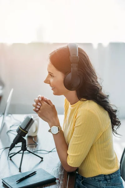 Jolie animateur de radio souriant assis près du microphone en studio — Photo de stock