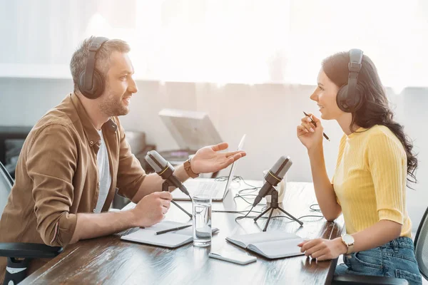 Two radio hosts in headphones talking while recording podcast in radio studio — Stock Photo