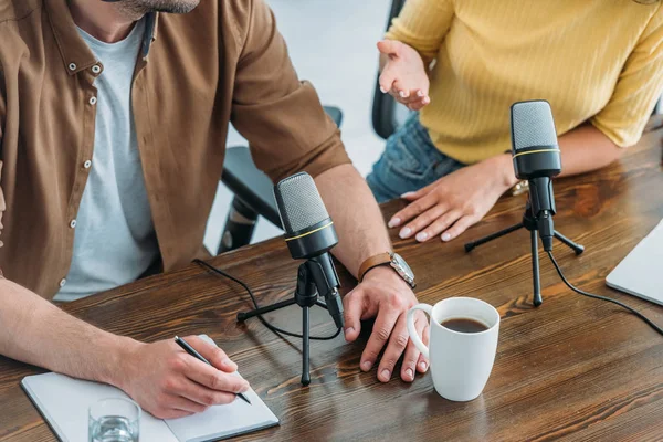 Partial view of two radio hosts sitting at workplace in broadcasting studio — Stock Photo