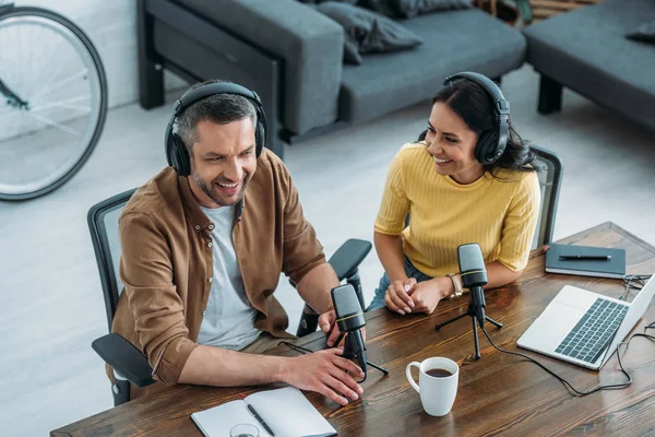 Dos anfitriones de radio alegre hablando mientras está sentado en el lugar de trabajo en el estudio de radiodifusión - foto de stock