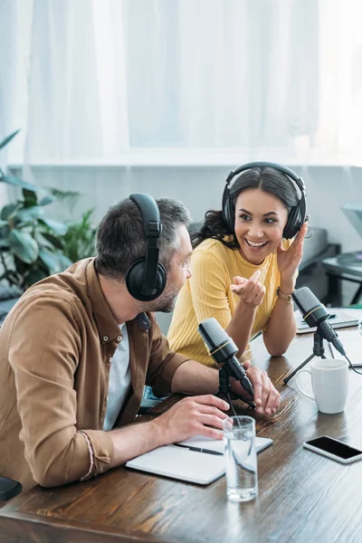 Jolie animateur radio souriant et gestuel tout en enregistrant podcast avec collègue — Photo de stock