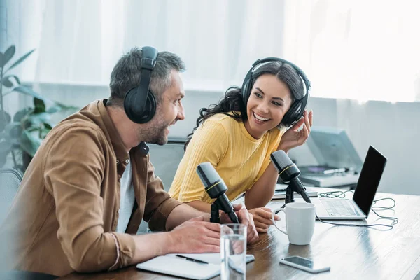 Two smiling radio hosts talking while recording podcast in studio together — Stock Photo