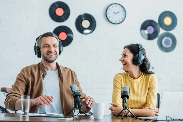 Zwei gut gelaunte Radiomoderatoren im Kopfhörer, die gemeinsam einen Podcast im Studio aufnehmen — Stockfoto