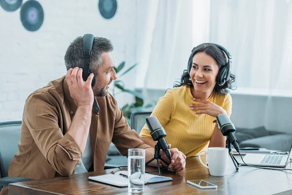 Two cheerful radio hosts in headphones recording podcast in broadcasting studio — Stock Photo