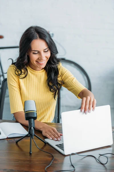 Lächelnde Radiomoderatoren öffnen Laptop, während sie im Studio neben Mikrofon sitzen — Stockfoto
