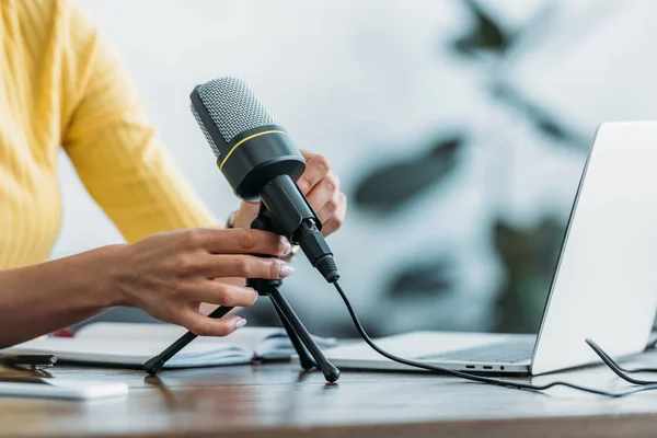 Vista ritagliata dell'host radio che regola il microfono mentre è seduto sul posto di lavoro in studio — Foto stock