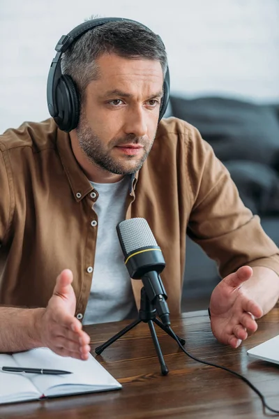 Serios gestos de anfitrión de radio mientras habla en micrófono en estudio de radiodifusión - foto de stock