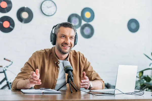 Anfitrión de radio alegre gesto mientras habla en micrófono en estudio de radiodifusión - foto de stock