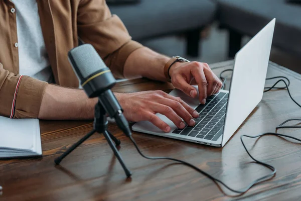 Cropped view of radio host using laptop while sitting at workplace in broadcasting studio — Stock Photo