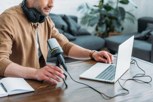 Vue recadrée de l'hôte radio à l'aide d'un ordinateur portable assis près du microphone — Photo de stock