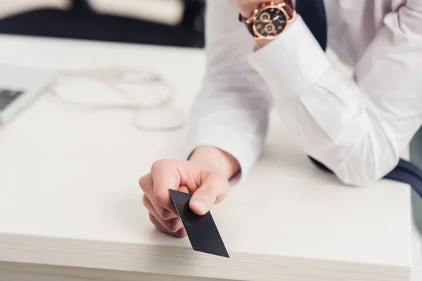 Vue recadrée d'un homme d'affaires tenant une carte de visite noire vide dans son bureau — Photo de stock