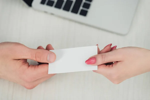 Ausgeschnittene Ansicht von männlichen und weiblichen Händen mit weißer leerer Visitenkarte in Laptopnähe — Stockfoto