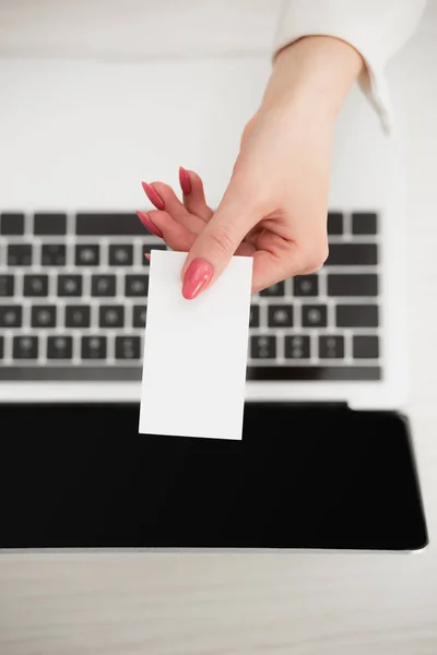 Vista dall'alto della donna d'affari che tiene bianco biglietto da visita vuoto vicino al computer portatile — Foto stock