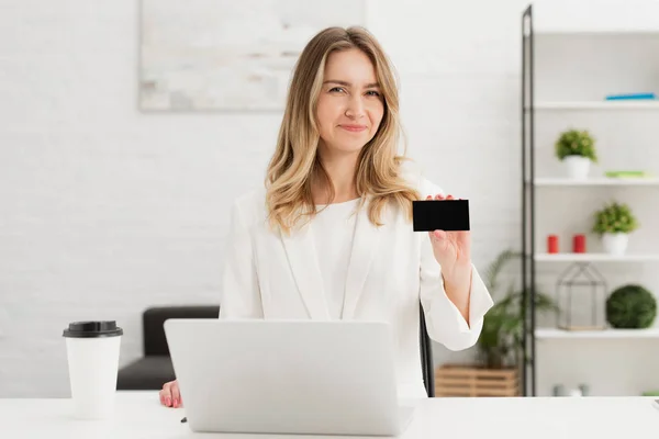 Pretty businesswoman looking at camera and showing blank empty business card — Stock Photo