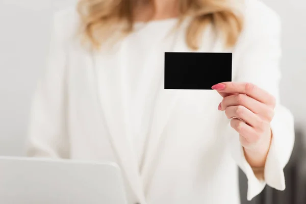 Cropped view of businesswoman showing at camera empty black business card — Stock Photo