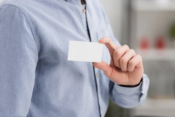 Vista parcial del hombre de negocios con tarjeta de visita blanca en blanco en la oficina - foto de stock